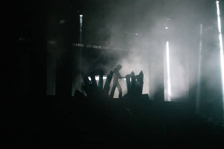 Silhouette of a performer on stage amidst intense lighting and smoke effects.