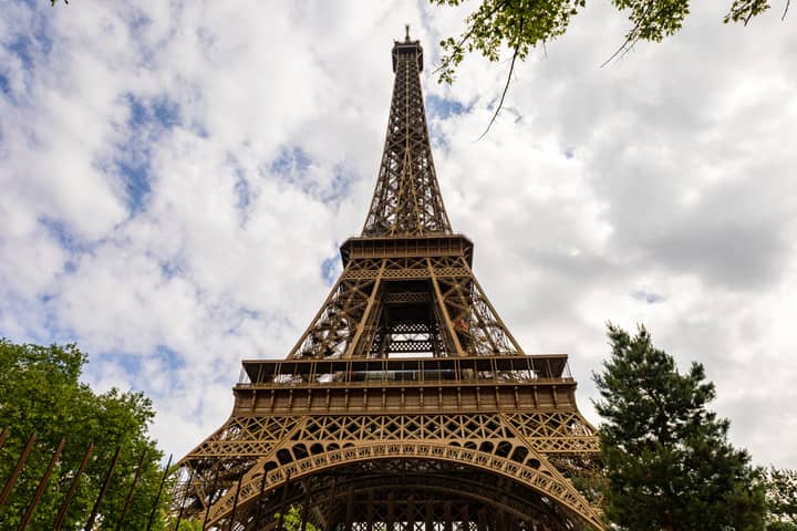 A captivating upward view of the Eiffel Tower against a cloudy sky in Paris.