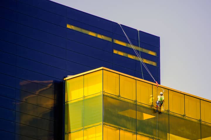 Professional window cleaner at Guthrie Theater in Minneapolis using safety harness.