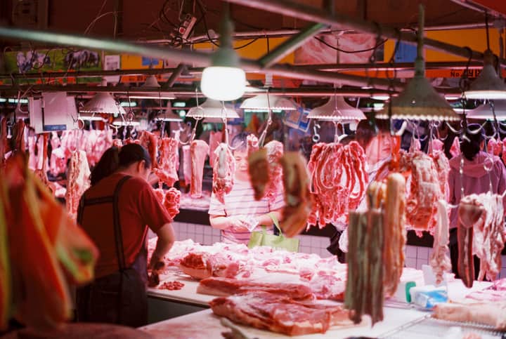 A vibrant scene capturing customers and vendors in a bustling indoor meat market.
