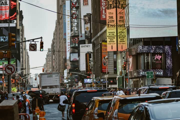Street view of busy traffic and colorful billboards in Times Square, NYC.
