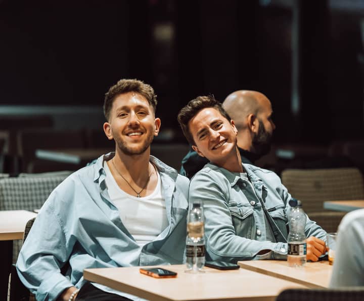 Two friends smiling and enjoying a relaxed moment indoors at a cafe or meeting space.
