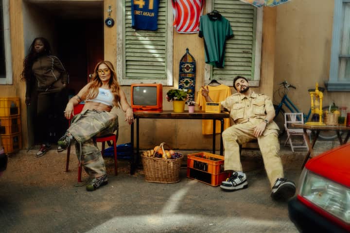 Casual urban scene with three adults, retro TV, and vintage decor in a city setting.