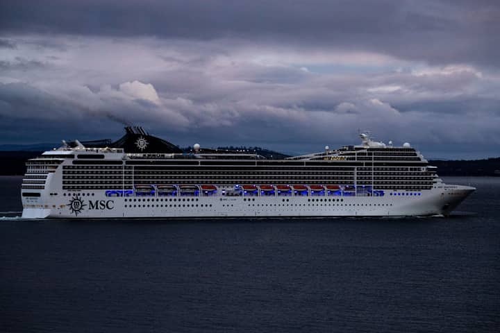 MSC cruise ship navigating waters near Hobart, Tasmania against a dramatic cloudy sky.
