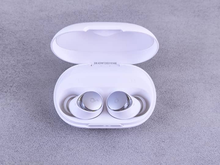 High-quality white wireless earbuds displayed in an open charging case on a textured surface.