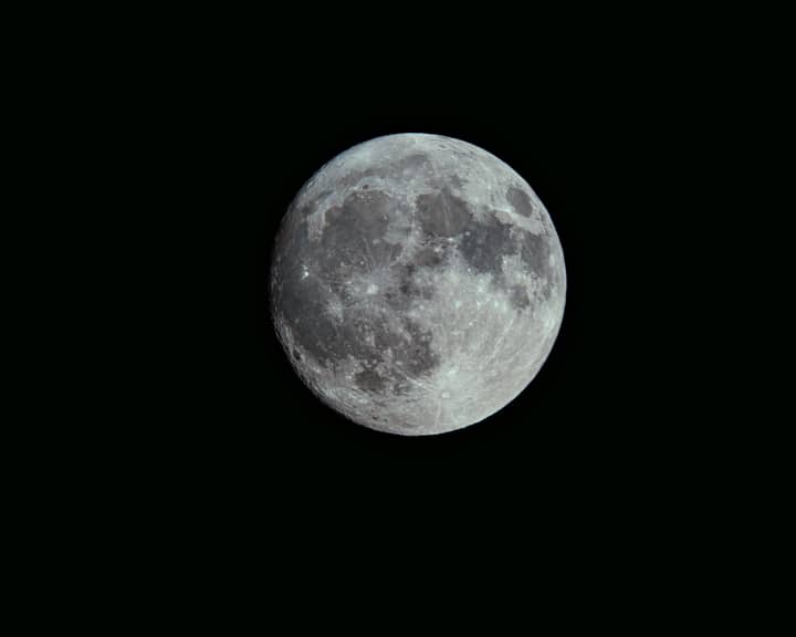 A detailed photograph capturing the full moon with visible craters and dark night sky backdrop.