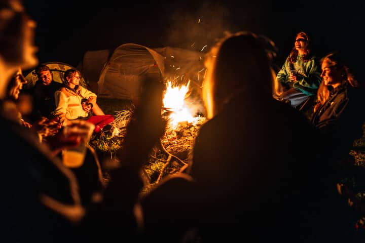 A cozy group campfire scene with friends enjoying a night outdoors in Schilpario, Lombardia, Italy.