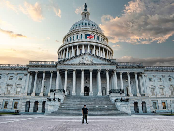 Front view of the iconic United States Capitol with dramatic evening sky.