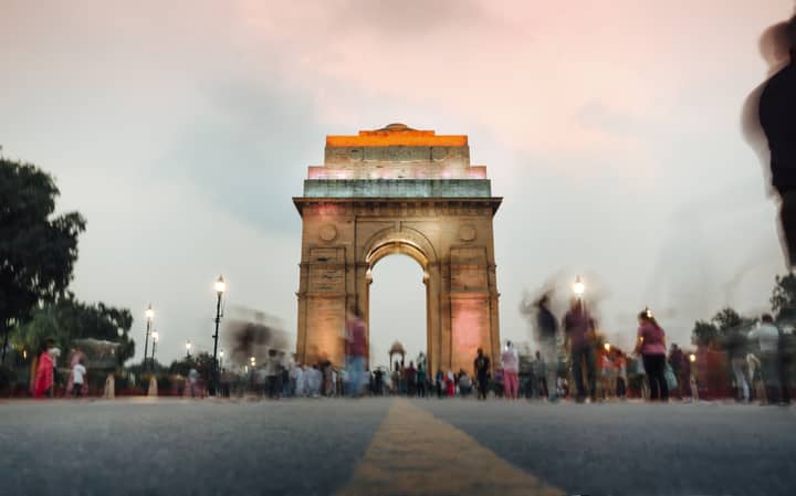 A stunning view of India Gate in New Delhi at sunset with a dynamic crowd.