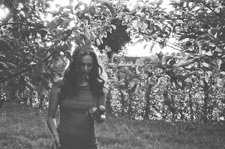 Woman in an orchard captures silent elegance in black and white.