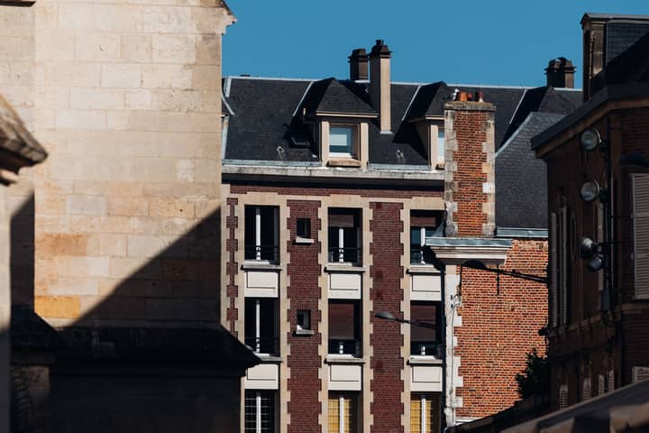 Historic brick and stone buildings under clear blue sky in Amiens, France.