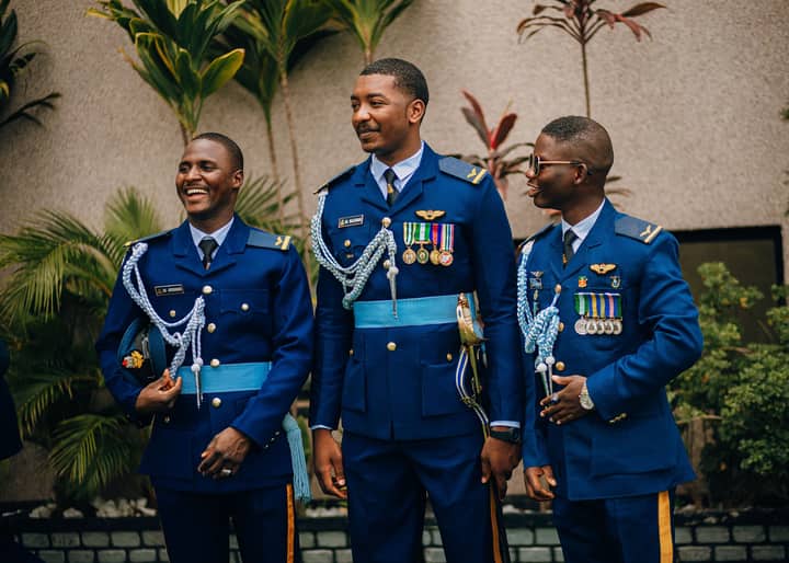 Three military officers in dress uniform adorned with medals, standing outdoors and smiling.