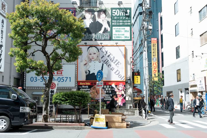 A vibrant street scene in Tokyo Japan featuring colorful billboards and pedestrians on a sunny day.