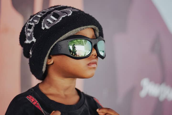 A young child wearing a cool beanie and reflective sunglasses, showcasing style and attitude.