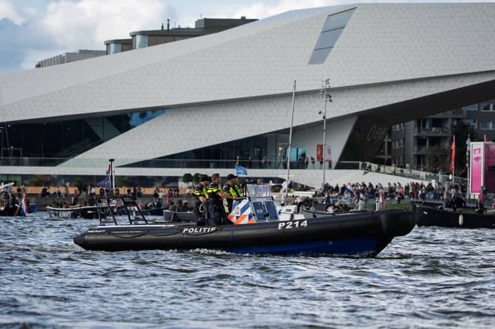 A police boat navigates near the Eye Film Museum on a vibrant day in Amsterdam.