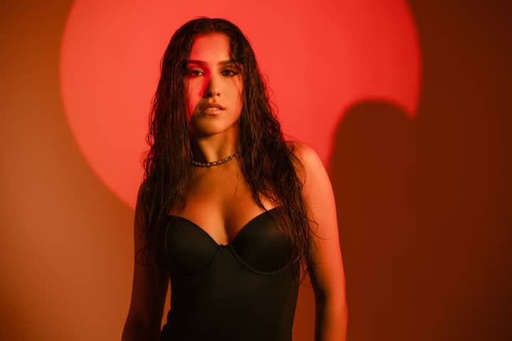 A striking portrait of a woman with bold red lighting and wet hair effect.