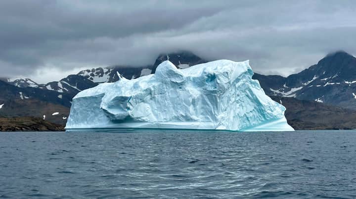 Expansive iceberg floating serenely in the cool waters of Greenland.