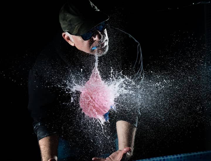 Dramatic scene of a water balloon exploding in mid-air with a person observing.