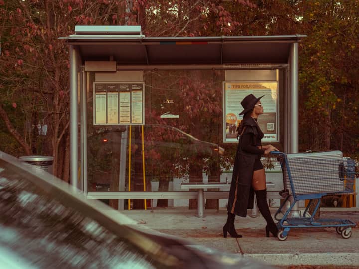 Stylish woman with a shopping cart at an outdoor bus stop in Atlanta, Georgia.