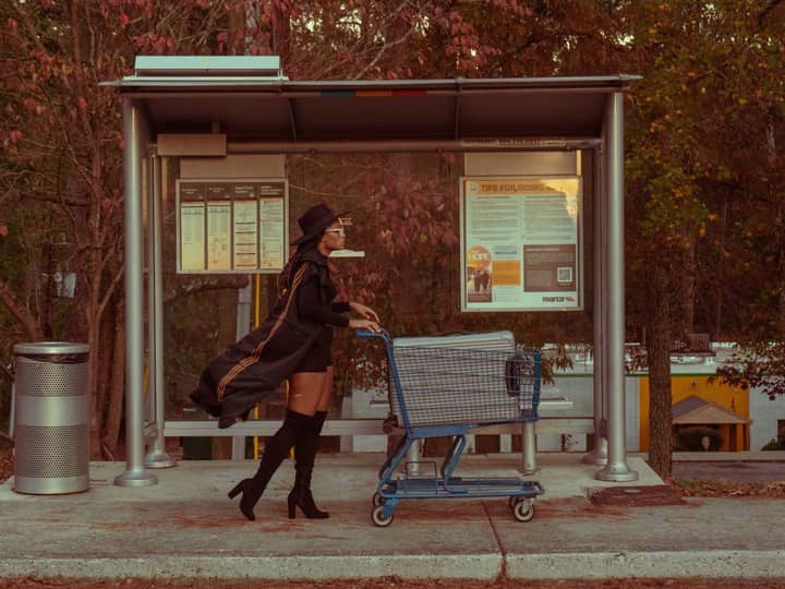 Stylish woman pushing a cart at an outdoor Atlanta bus stop in fall season.