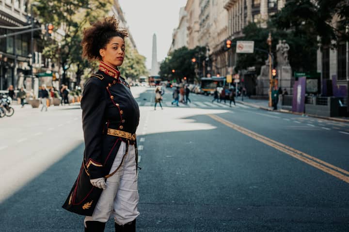 A woman in a historical military costume poses on a vibrant street in Buenos Aires, Argentina.
