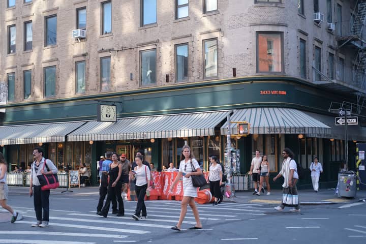 People crossing the street near Jack's Wife Freda cafe on a sunny day.