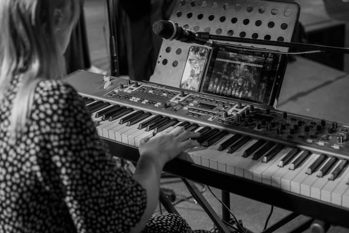 A woman playing a keyboard in a monochrome music setting. Artistic and professional.