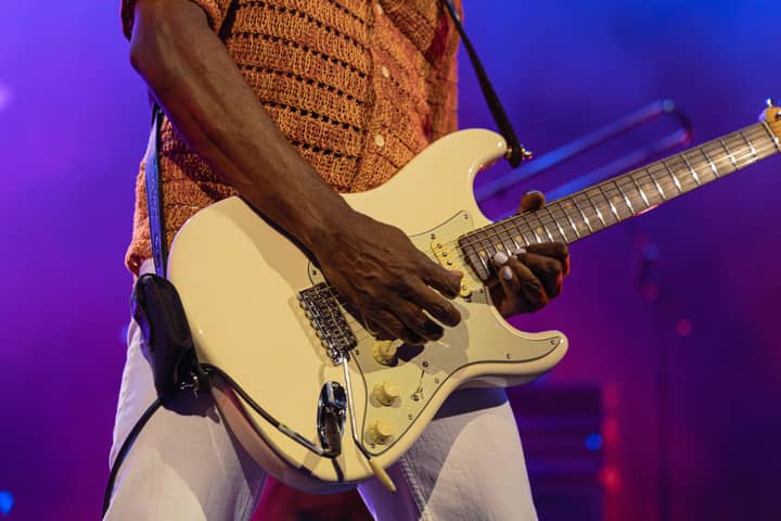 Close-up of a musician playing electric guitar at a vibrant live concert.