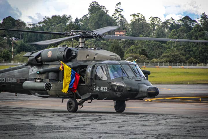 Colombian military helicopter with national flag on airport runway.