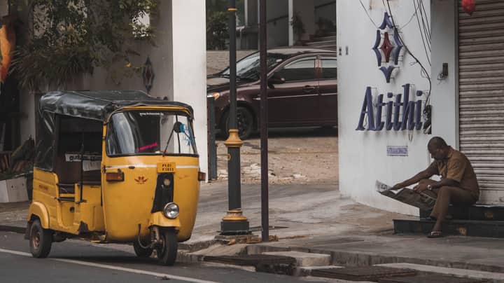 A vibrant yellow auto rickshaw parked on a street, capturing daily life in Puducherry, India.