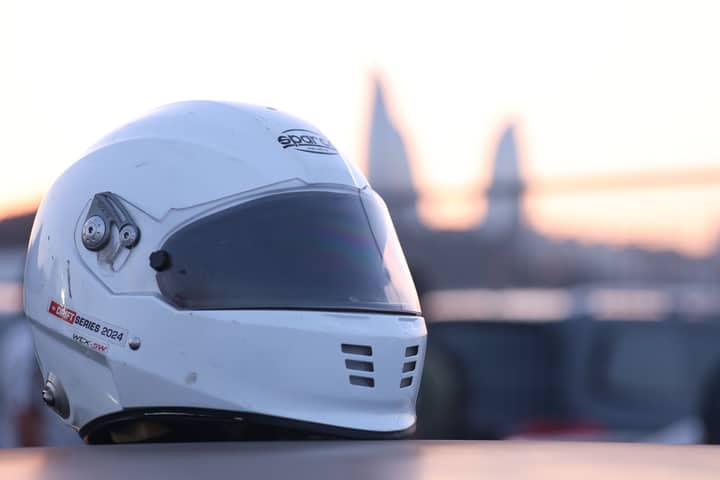 White racing helmet resting on a surface with a sunset backdrop, emphasizing motorsport passion.