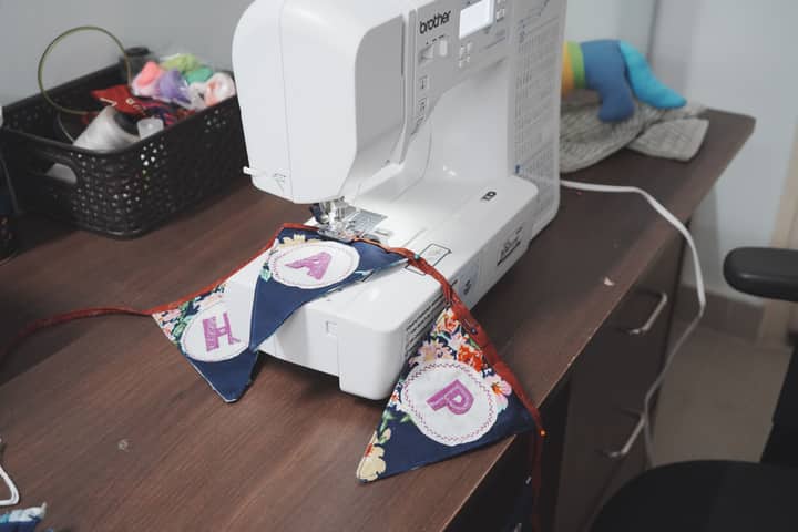 A sewing machine creates vibrant DIY bunting indoors, capturing the crafting process.