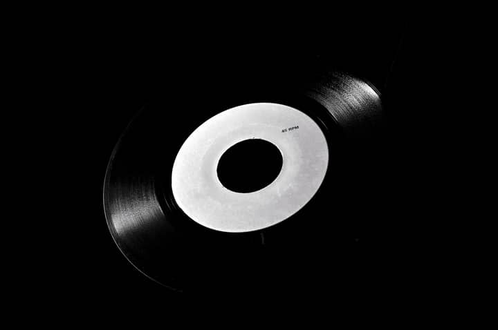 Classic black vinyl record with a white label on a dark background, symbolizing retro music nostalgia.