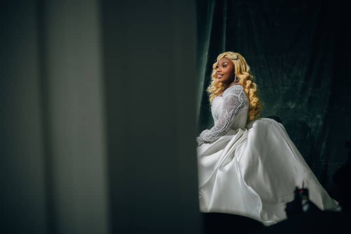 A stunning bride in a luxurious white gown with intricate lace details and long blonde hair.