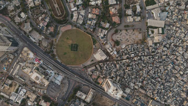 A detailed aerial shot of Karachi showing dense settlements and a distinct circular park, highlighting urban development.