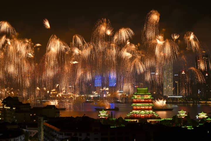 Dazzling fireworks illuminate a majestic pagoda and city skyline at night, creating a breathtaking spectacle.
