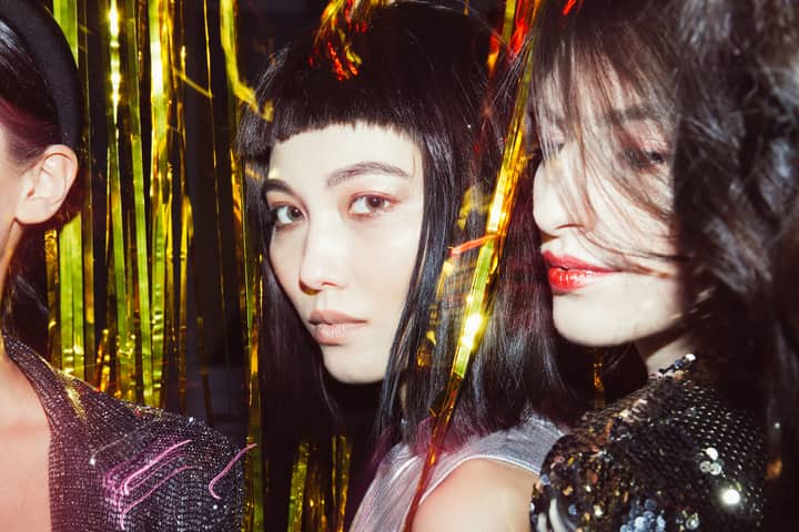 Close-up of fashionable women celebrating at a trendy party with golden decorations.