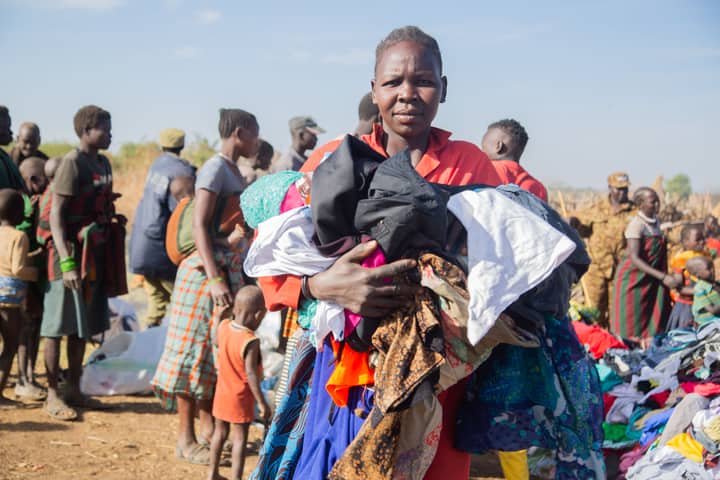 A community event where people receive donated clothing. A woman holds a bundle of clothes.