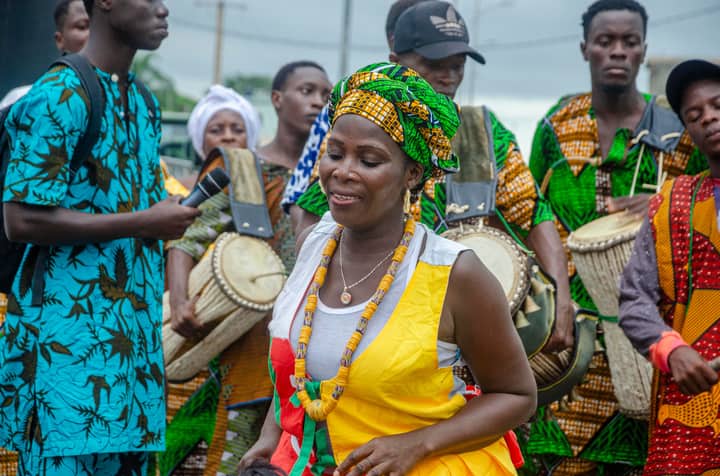 Colorful traditional West African drum performance with dancers and musicians outdoors.