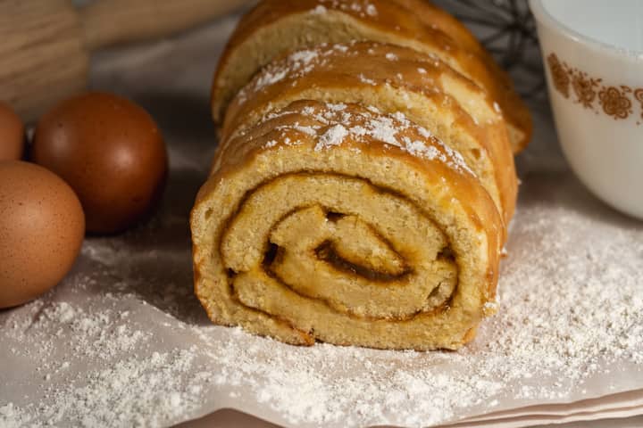 Tasty homemade Swiss roll cake surrounded by eggs and flour, perfect for baking enthusiasts.