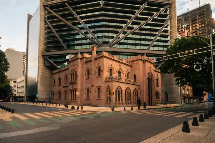 A historic architectural building juxtaposed with a modern skyscraper in Mexico City.