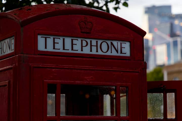 Classic red telephone booth set against a modern London skyline, showcasing British heritage.