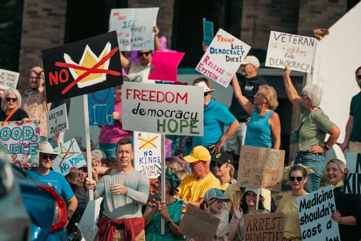 A diverse group of protesters holds signs advocating for freedom and democracy at a daytime rally.