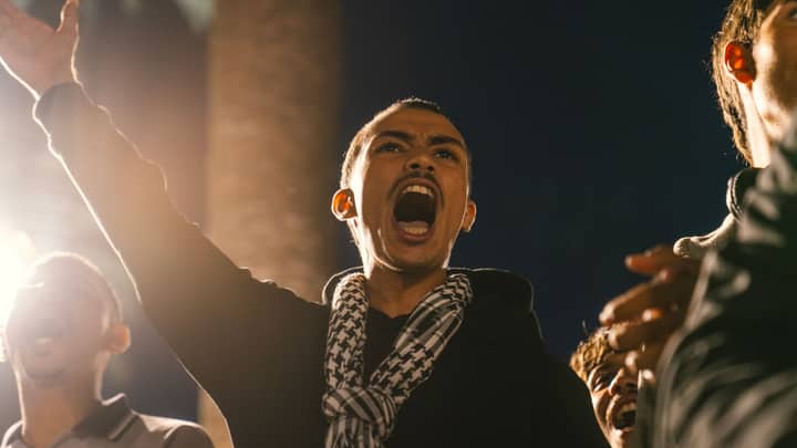 A young protestor passionately shouting during a nighttime rally in Rabat, Morocco.