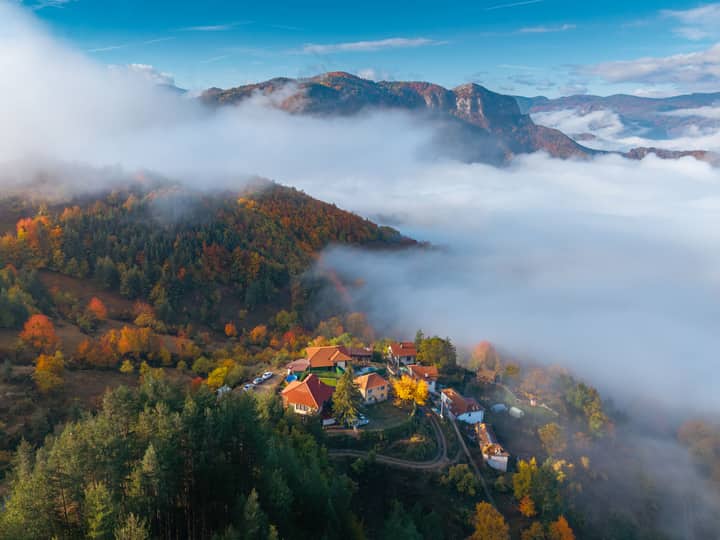 Stunning aerial shot of the Rodopi Mountains showcasing vibrant fall foliage and misty valleys.