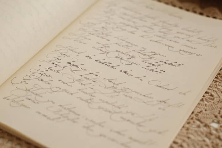 A vintage open journal with elegant handwritten script on a lace tablecloth.