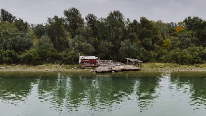 A serene view of a riverside with a rustic structure in Belgrade, Serbia.