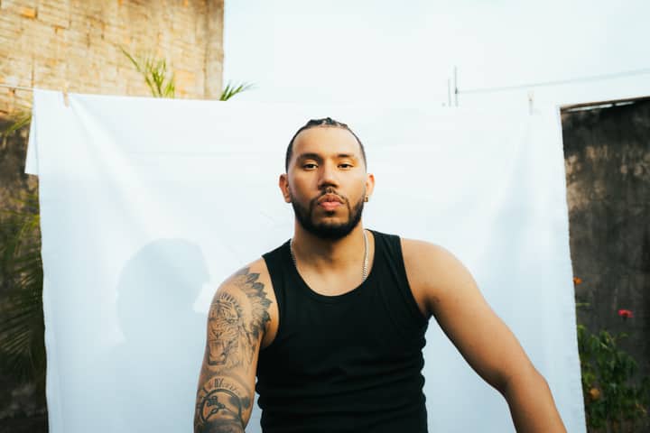 Portrait of a tattooed man with braids sitting outdoors in Presidente Prudente, Brazil.