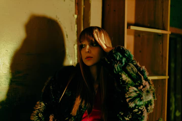 Mysterious woman in a fur coat posing indoors with dramatic lighting.