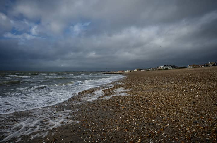 Moody beach scene at Lee-on-the-Solent, England, with stormy skies and waves crashing ashore.